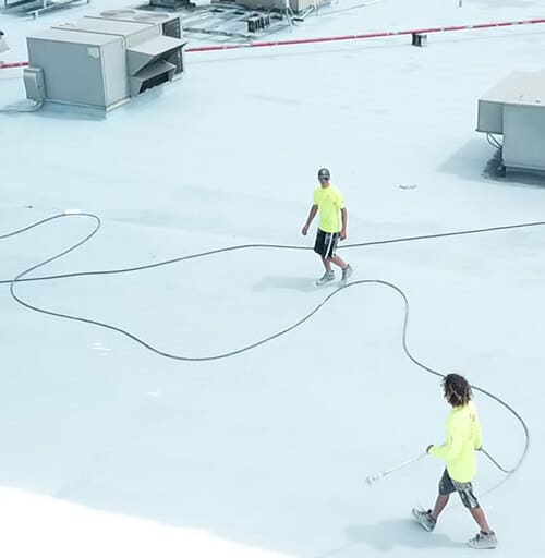 Contractors spray flat roof coating.