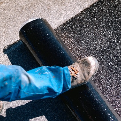 A commercial roofer works on a roof.